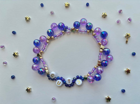 Olivia Rodrigo GUTS beaded bracelet decorated with butterflies, stars, lettering and purple beads.